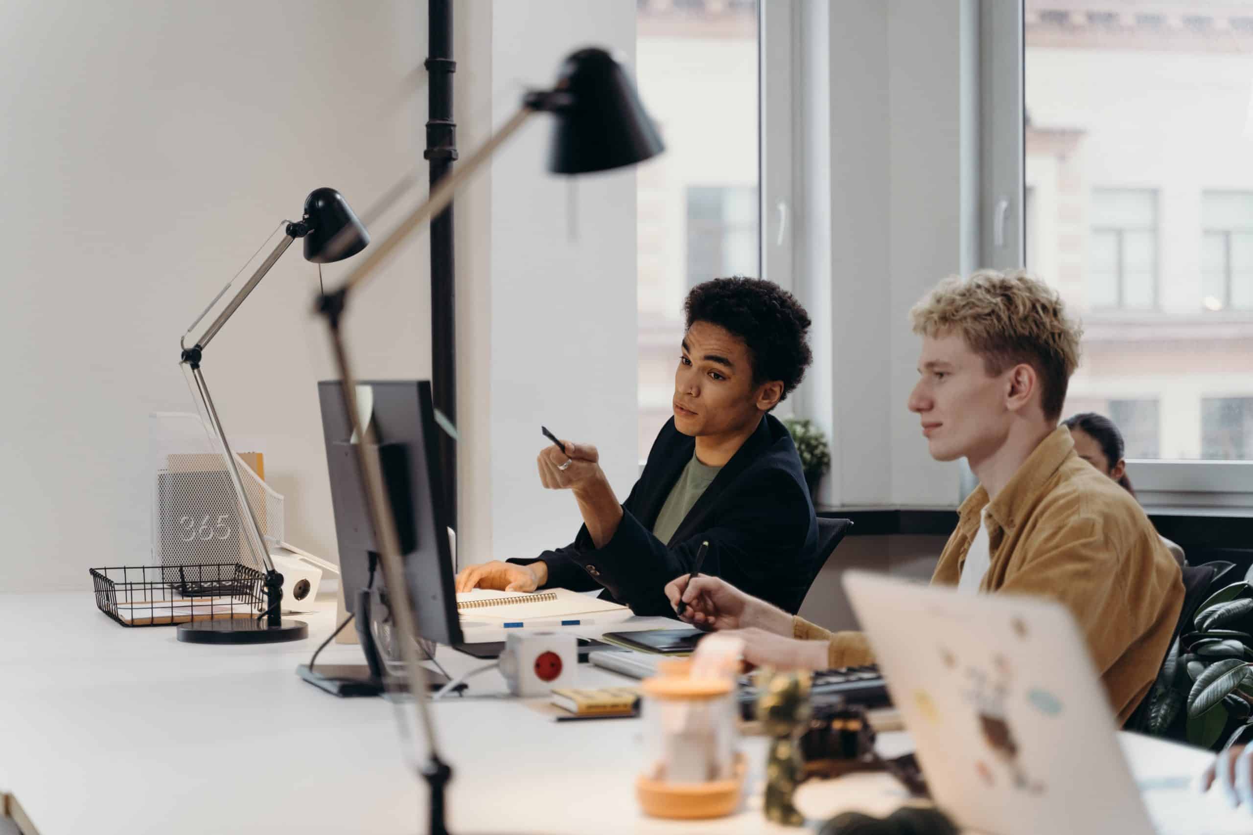 Two team members collaborating in front of a computer screen