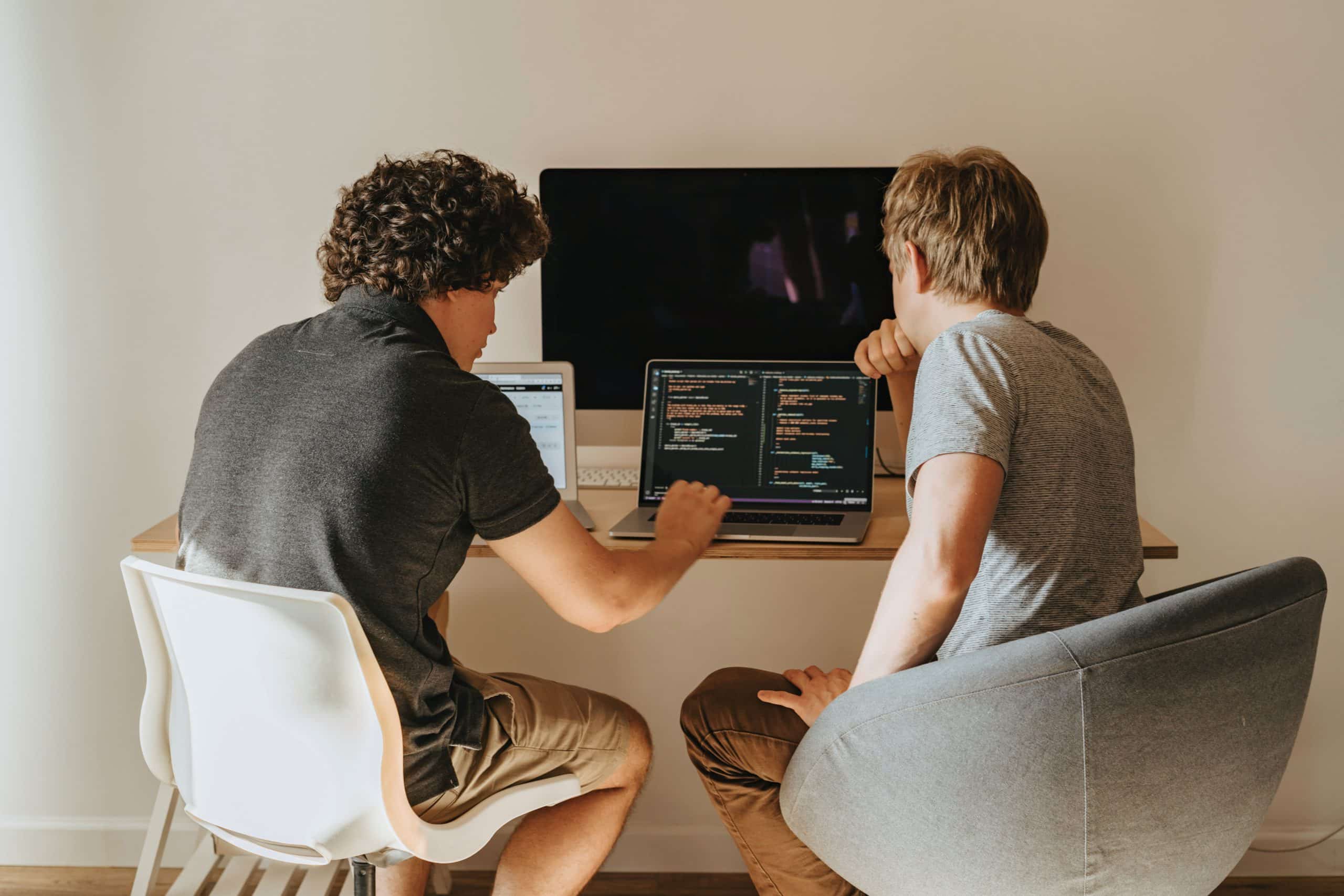 Two men looking at a computer screen and collaborating on a software development project.